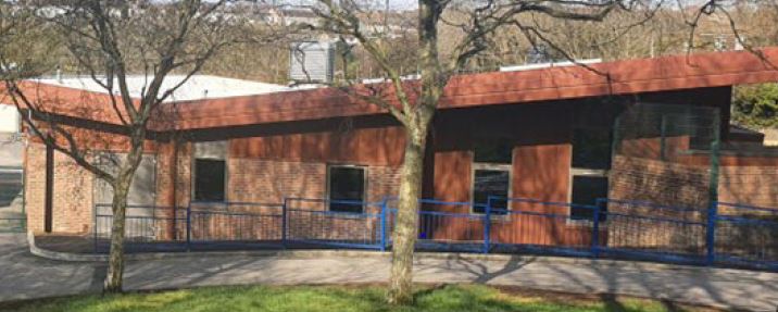 Photo of Hove Park School Cullum Centre, trees to the front with a blue metal railing.