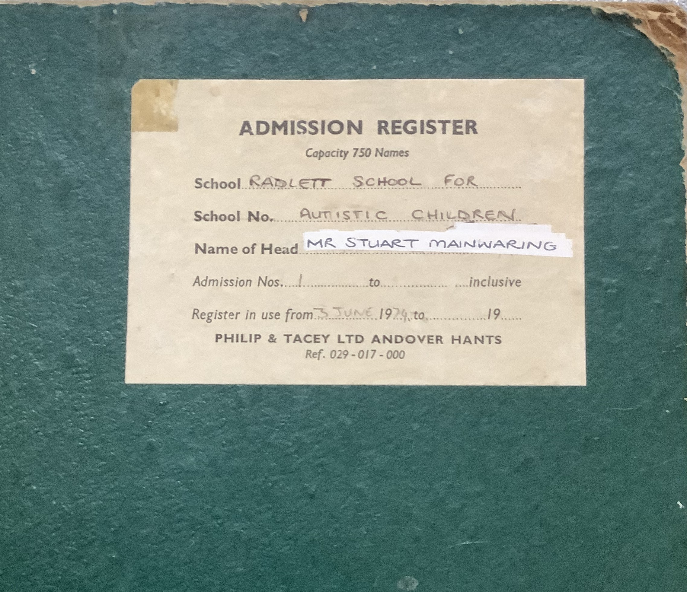 An admissions log with a green cover, this dates back to the school opening.